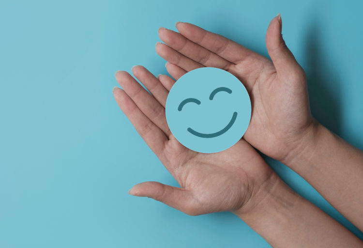 Smiling face in palms on a turquoise background